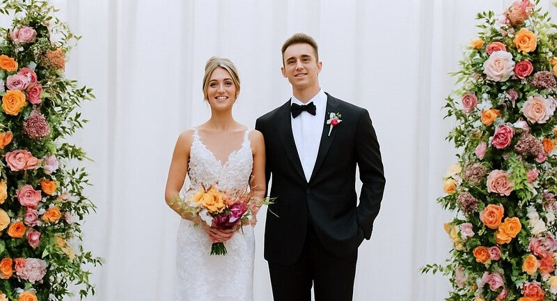  Bride and groom pose with vibrant, locally sourced floral pillars by Flowers for Dreams.