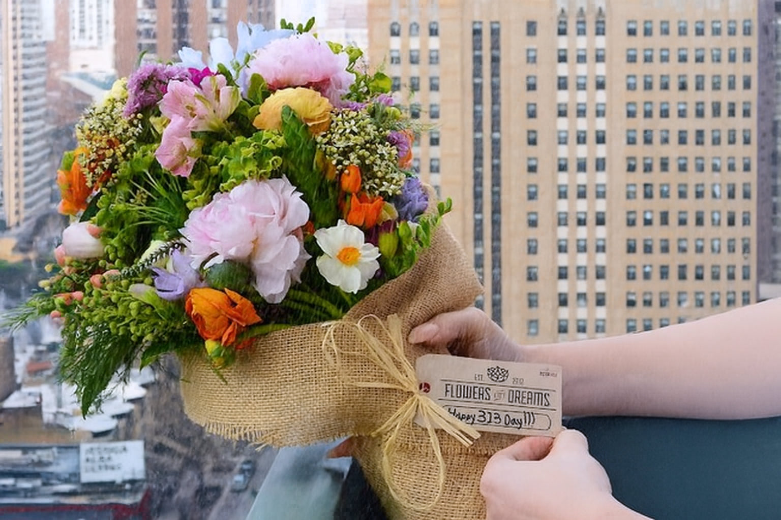 Hands holding wrapped fresh flower bouquet in burlap at Flowers for Dreams in Detroit.