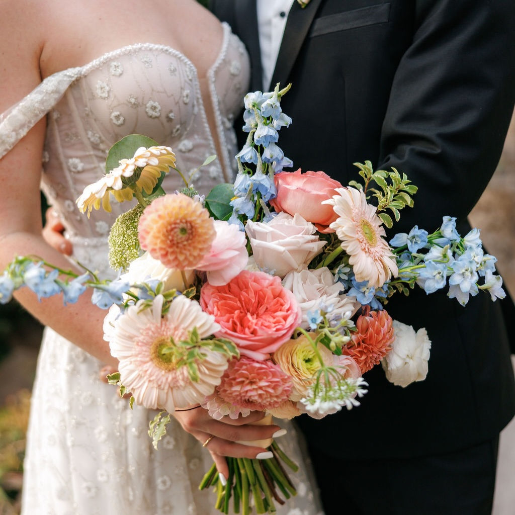Bride holding a romantic summer wedding bouquet with seasonal blooms designed by Flowers for Dreams.