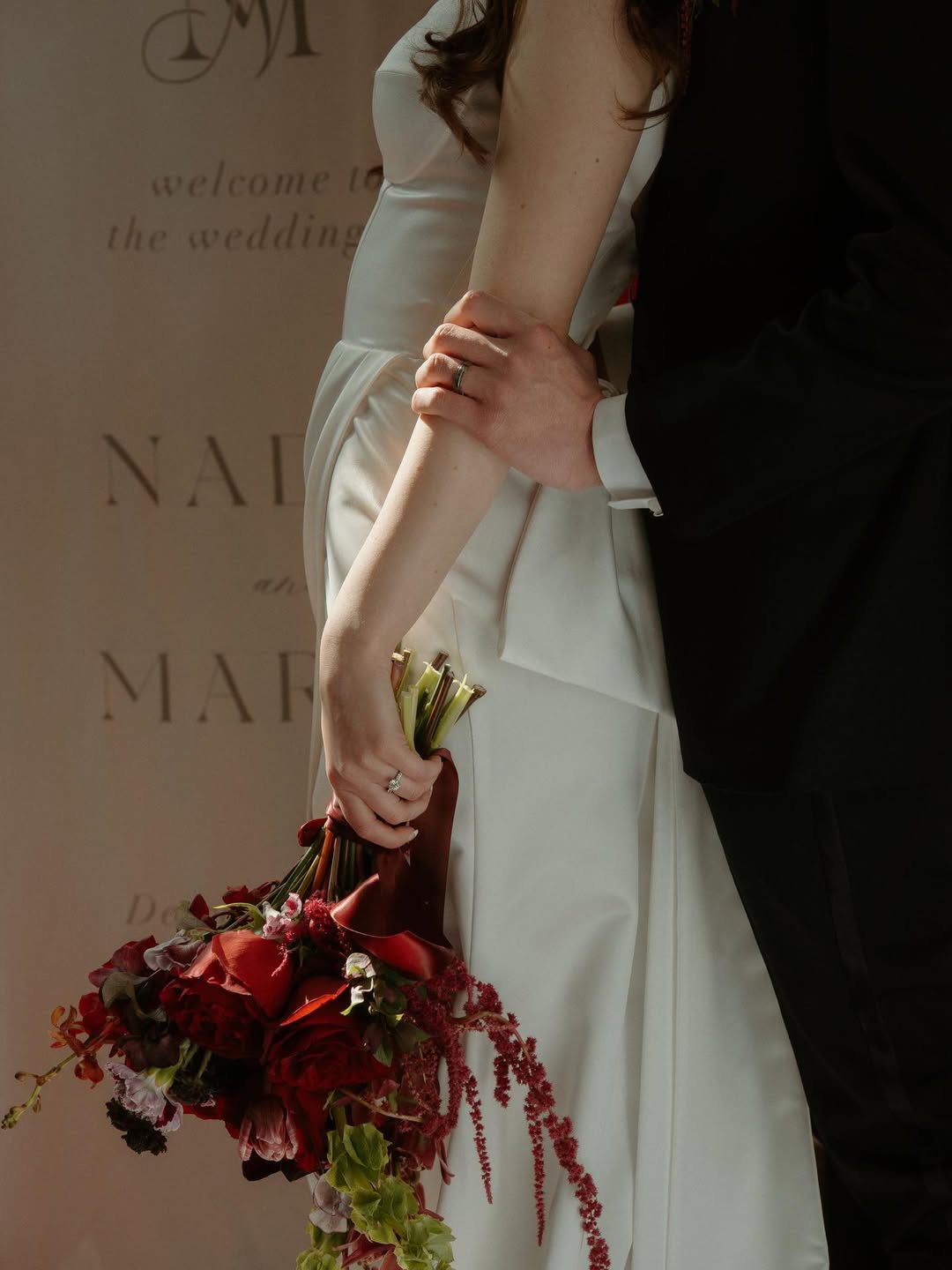 A picture of a woman in a wedding dress holding a bouquet by Flowers for Dreams, as her partner stands behind her.