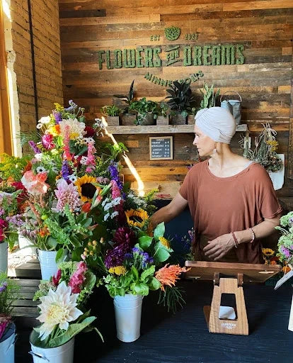 Flowers for Dreams' Milwaukee studio featuring a florist arranging colorful bouquets behind a flower-filled counter.