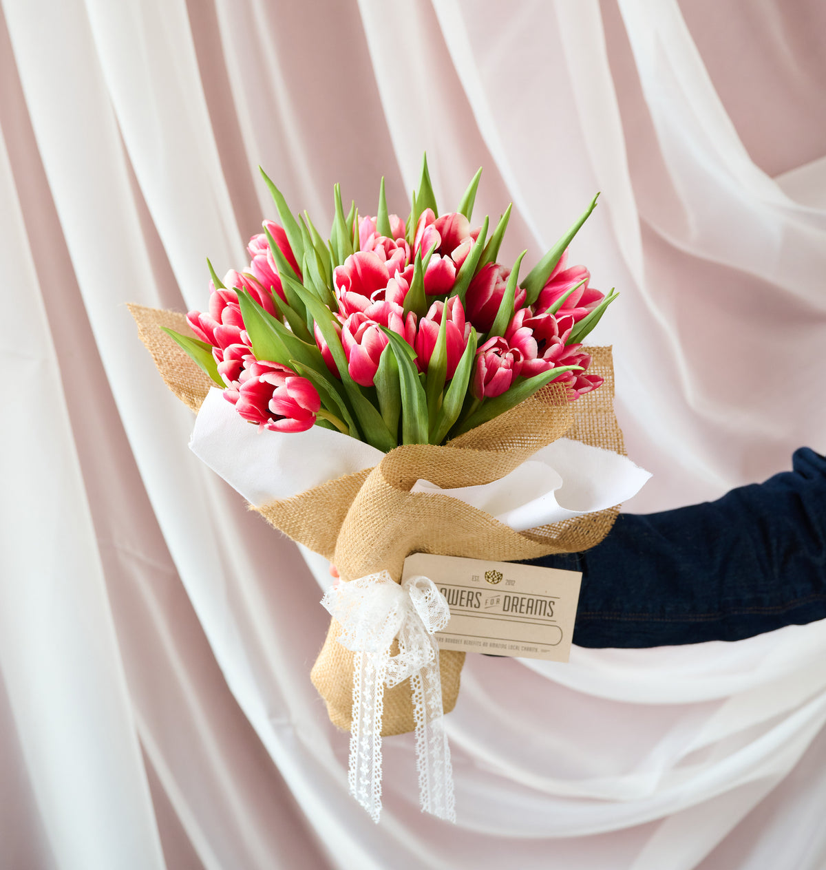 Fresh pink tulips arranged in a clear glass vase, featuring soft seasonal blooms with bright green stems, handcrafted by Flowers for Dreams.