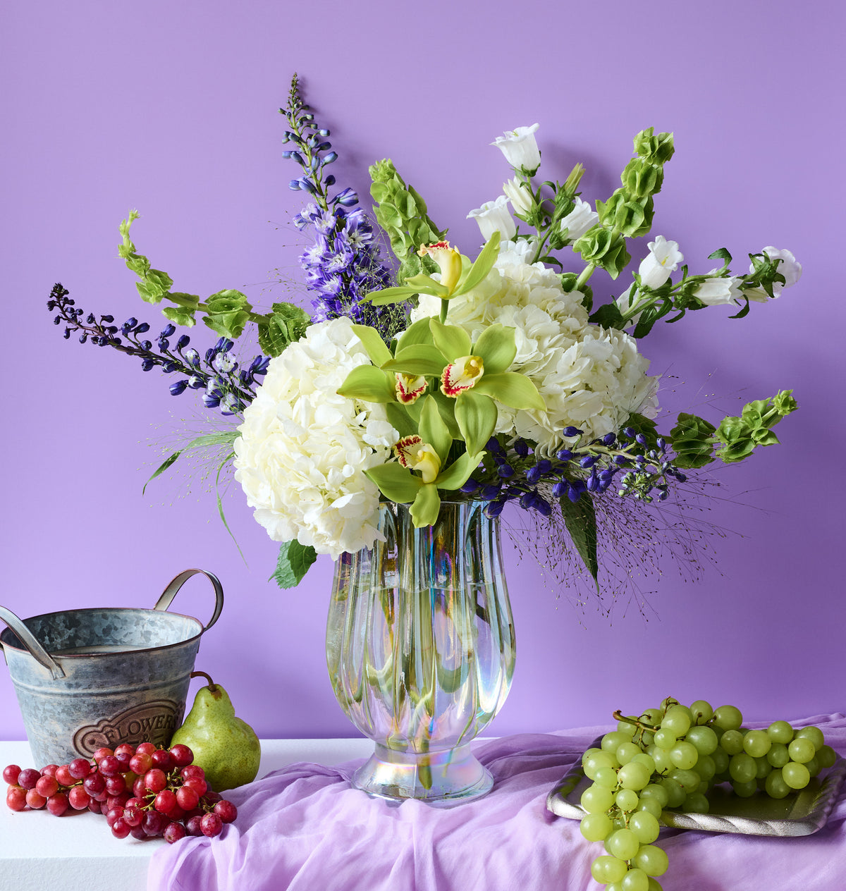 Botanica luxury flower arrangement featuring white hydrangeas, green cymbidium orchids, delphinium, and lush seasonal greenery