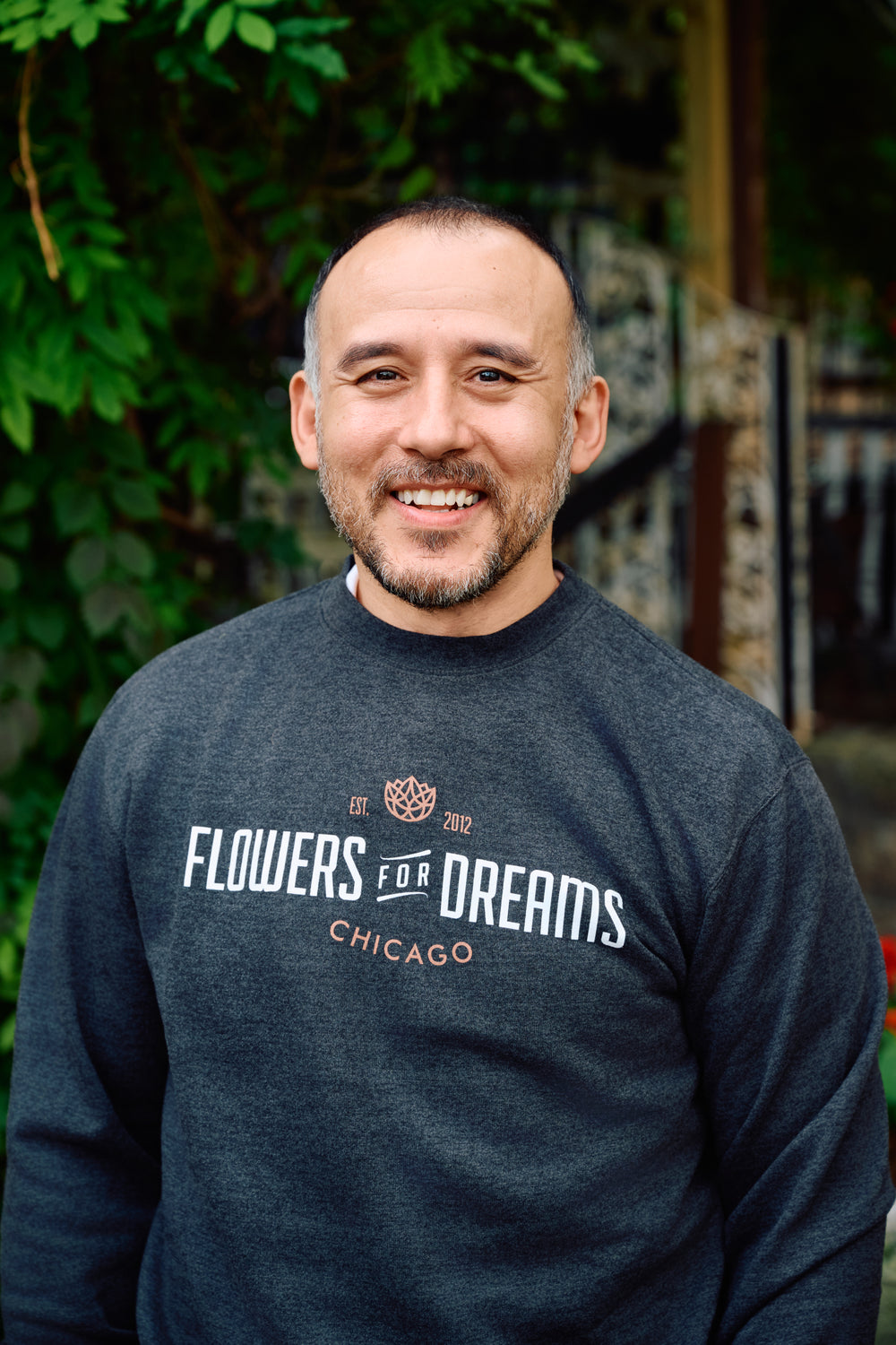 Man wearing a 'Flowers for Dreams Chicago' sweatshirt in an outdoor setting