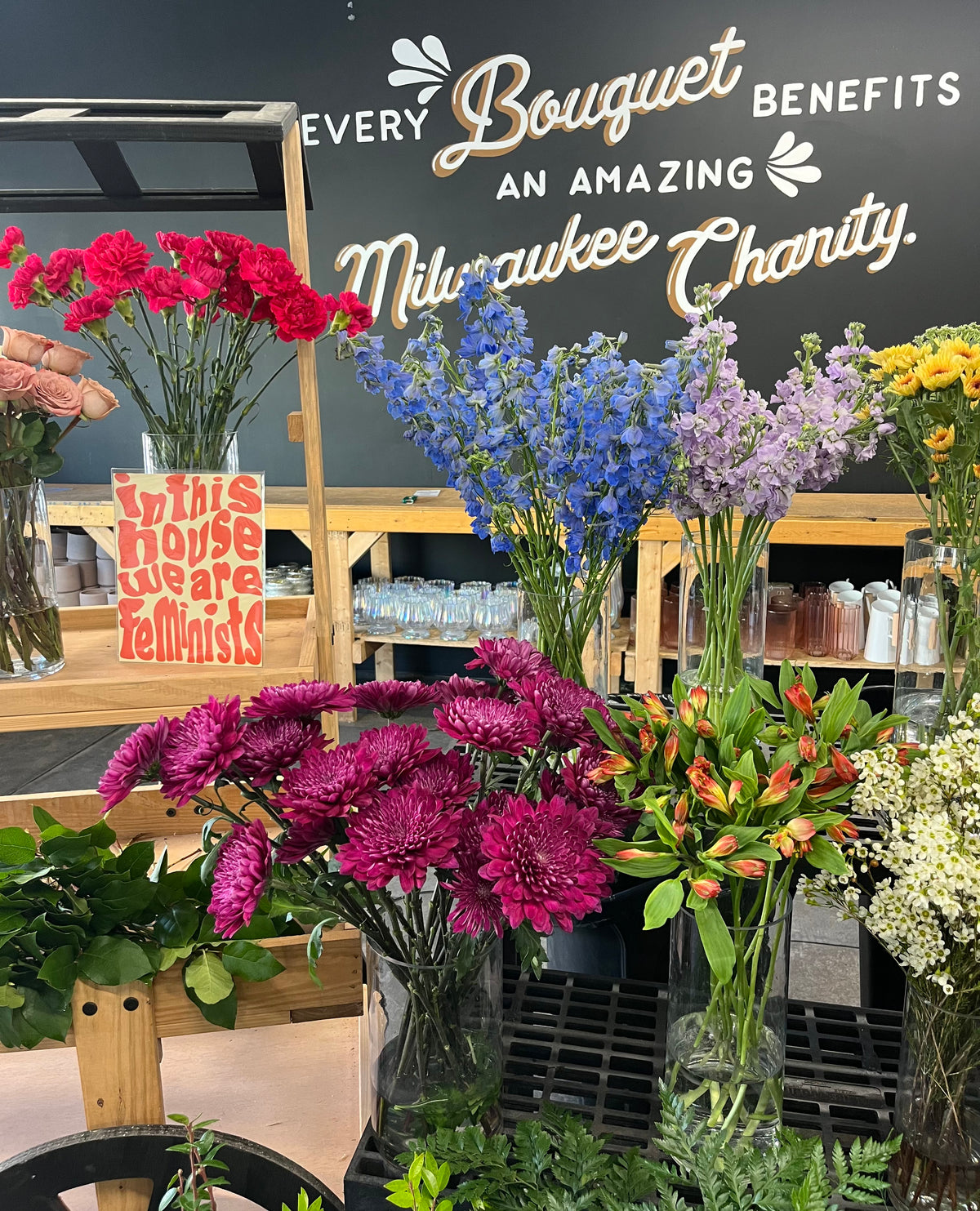 Bouquets of flowers displayed in a store with a sign indicating every bouquet benefits a charity.