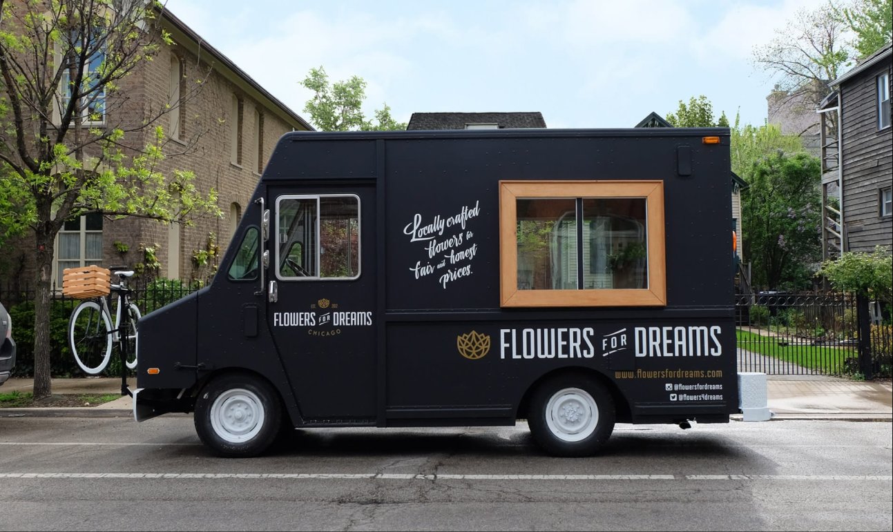 Black flower truck with 'Flowers for Dreams' branding on a street.