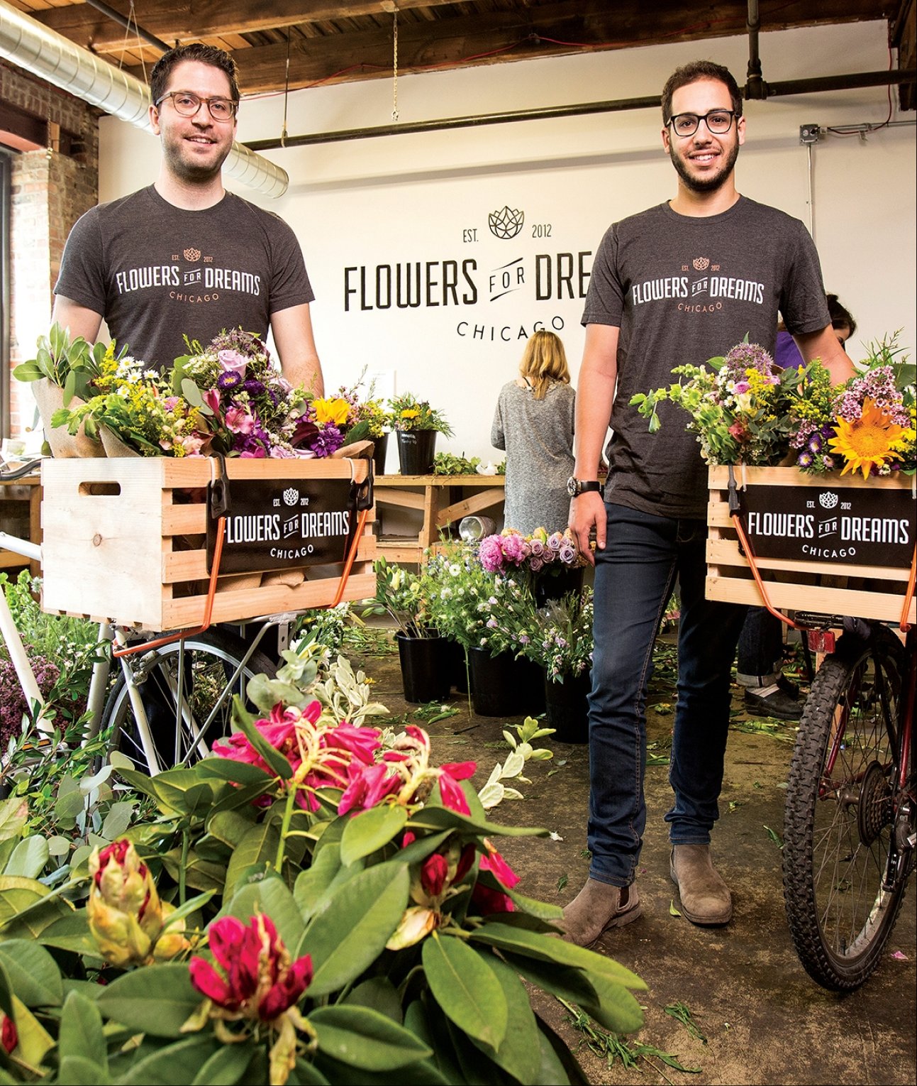 Founders standing with flower crates and floral arrangements in a warehouse setting, with 'Flowers of Dreams' branding.