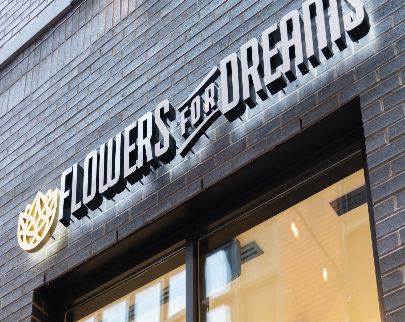 Brick building with 'Flowers for Dreams' sign above a store entrance